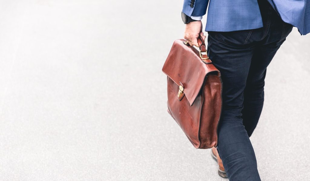 person walking holding brown leather bag